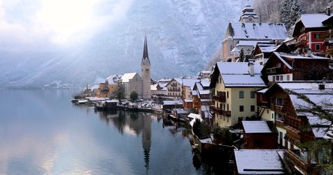 Panoramic camera move of the village of Hallstatt, Alps, Austria, during a sunny winter morning with snow and calm lake water