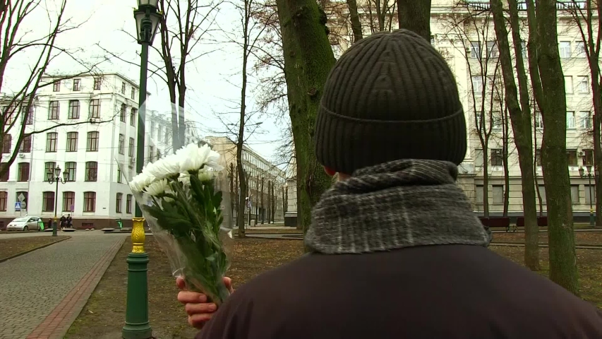 happy woman with a bouquet of white flowers hugs a man