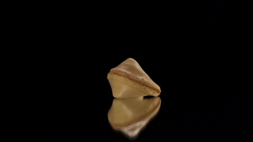 Chinese cookie rotate on a black background. Traditional fortune cookie.
