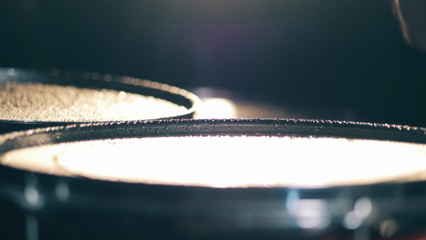 Drummer plays, hitting drums with water on it.