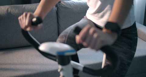 Close up of fitness woman in sport clothing exercising legs on static bike and wearing smart watch for measuring blood pressure. Concept of control and responsible attitude for health status Stock-video