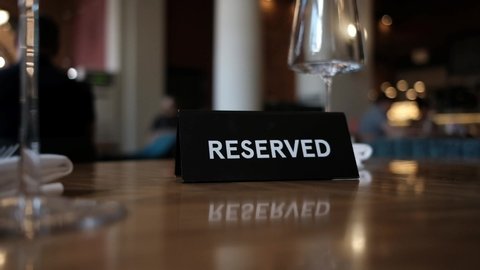 Reserved Table. A tag of reservation placed on the wood table. Reserved logo. Reservation sign. Plastic tag with reservation logo. Reserved table in a restaurant. Hungry.