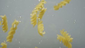 Fusilli pasta falls into the water, close-up, slow motion. Cooking the pasta. - Powered by Shutterstock - Get 15% off with code: PIKWIZARD15