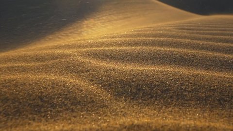 Sand storm in desert. Сamera moves along surface of sand dune in the desert in the rays of the setting sun. Sand waving in the wind. Slow motion shot.