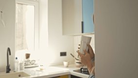 A laughing young woman is drinking water in the kitchen at home