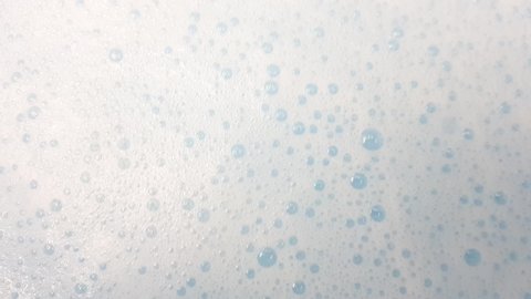 White foam with bubbles popping in blue water
