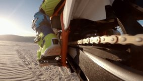 Shot from action camera mounted on the rear swingarm of a dirt motorbiker riding on sand dunes. Dirt biker off roading on sand dunes in desert.