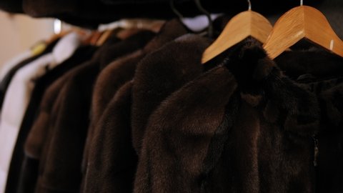 Fur products store. Many different coats of different fur on hangers in the clothing store. Grey mink coat on a mannequin in a women's clothing store.