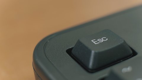 Human finger repeatedly pressing the escape key on a black keyboard.