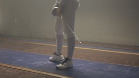 Pan up on a female fencer holding a epee preparing to duel in a fencing foggy gym on a strip - Powered by Shutterstock - Get 15% off with code: PIKWIZARD15