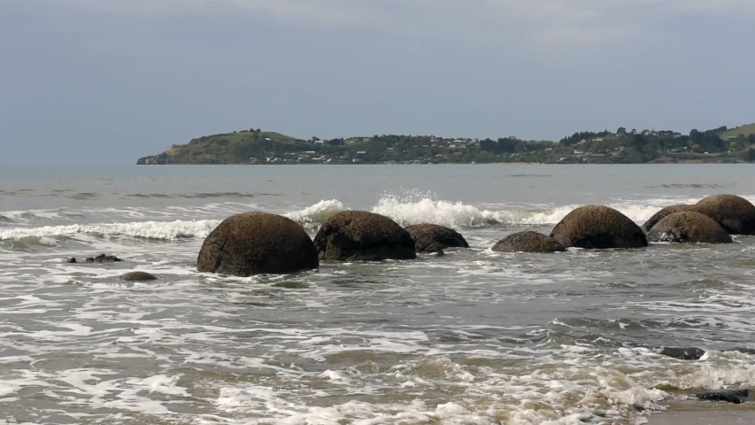 Moeraki boulders in the surf on Koekohe Beach on the Otago coast, New Zealand. 