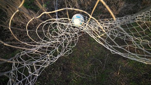 Kyiv, UKRAINE - January 2, 2020: Ball in the net. Goal. Missed ball. Losing. Football goal. The ball flies into the goal. Soccer player scores a goal. Close-up of the grid. Old football field.  