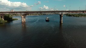 Beautiful 4k aerial video view on bridge with cars under river Dnipro wear swim 
barge in Kiev
