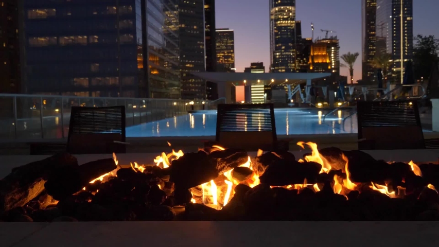Modern fireplace burning with houston cityscape in the background tracking shot