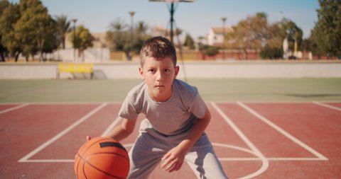 Cute kid hiting a basketball ball. Boy practicing shooting a basketball.