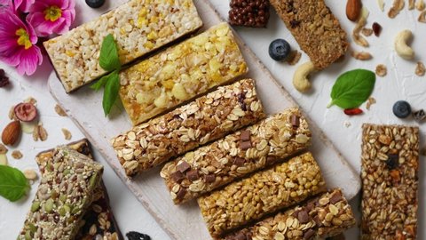 Homemade gluten free granola bars with mixed nuts, seeds, dried fruits on white stone background. Top view.