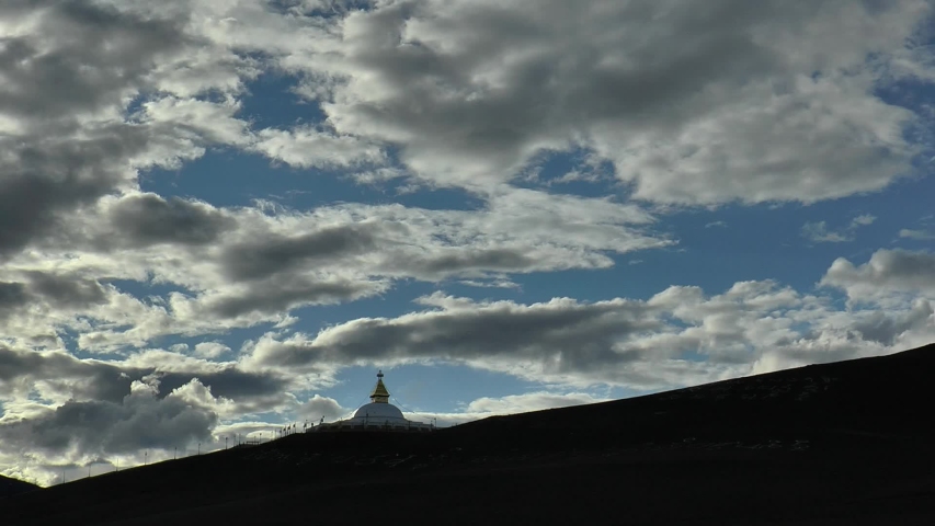 Stupa, or suburgan (Buddhist ritual structure) at sunset under a cloudy picturesque sky on a summer evening. 