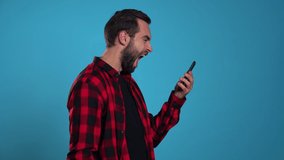 Angry modern hipster in red plaid shirt screaming down his mobile phone. Stressed and depressed man on blue background. - Powered by Shutterstock - Get 15% off with code: PIKWIZARD15
