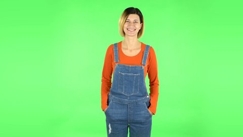 Woman standing, spreads out in a smile and looks at the camera. Green screen