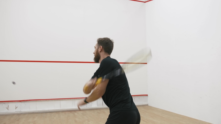 A portrait of a young bearded man practicing to play squash, slow motion