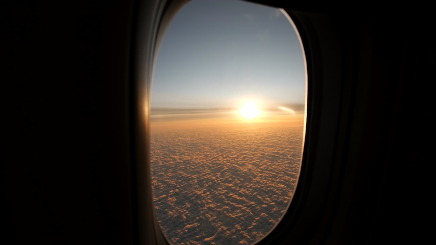 View from plane window sunshine clouds. Looking through window aircraft during flight in wing at sunset or sunrise. Clouds, sun and sky through window of airplane. Travel tourizm trip. 4 K slow-mo | Shutterstock HD Video #1046160787