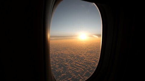 View from plane window sunshine clouds. Looking through window aircraft during flight in wing at sunset or sunrise. Clouds, sun and sky through window of airplane. Travel tourizm trip. 4 K slow-mo