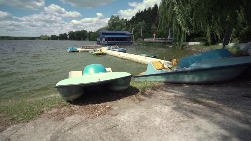 Wide view of iron boats moored on the shore of a lake. Slow motion.