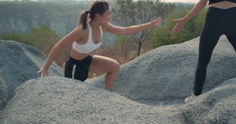 SLOW MOTION, Trail Running partners helping in the rock mountain climb up, Athlete fit two women exercise runners professional outdoor at beautiful nature difficult and challenging healthy lifestyle
