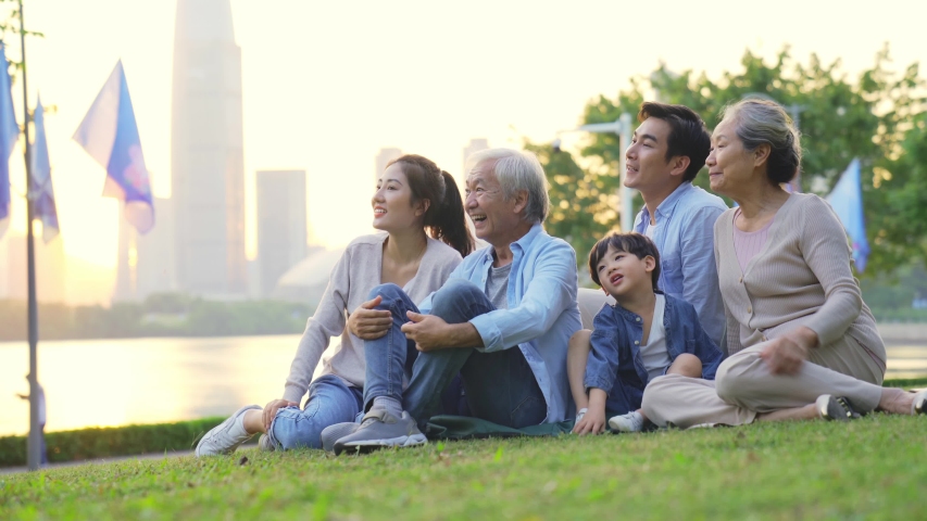 happy three generational family relaxing sitting on grass in city park Royalty-Free Stock Footage #1046166079
