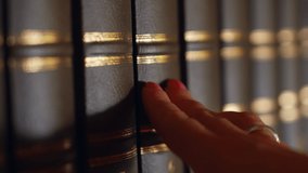 Woman hand choosing a book on the table in library, shallow depth of field. Books with a luxurious leather binding. 4k - Powered by Shutterstock - Get 15% off with code: PIKWIZARD15