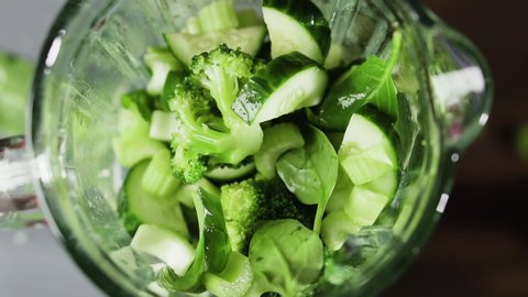 Vegetables fall in blender, slow motion. Green smoothie in blender, top view. Healthy eating concept.