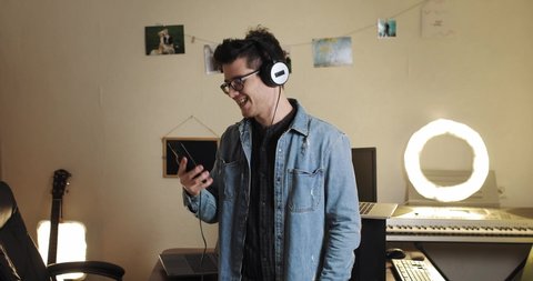 a nice guy female blogger in a denim jacket and jeans with glasses sing and dance in headphones