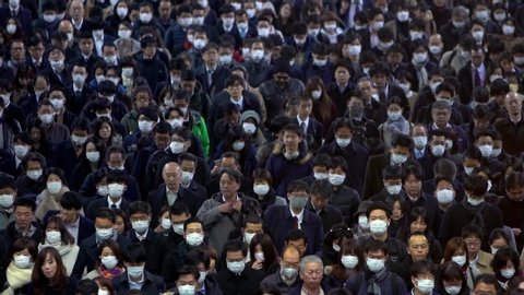 Tokyo, Japan-04 February, 2020: Slow motion of aerial view large crowd people wearing surgical mask walking in subway exit. Coronavirus pneumonia spreading into cities. 2019-nCoV epidemic of China