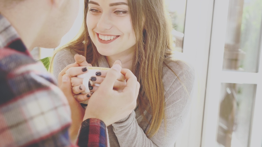 Smiling lovely couple are sitting in cafe. They are holding a cup of hot coffee. Close up view. 