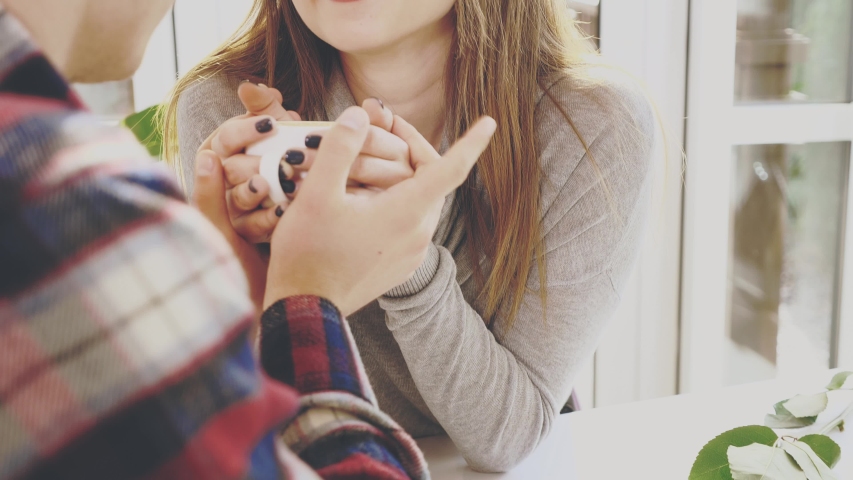 Smiling lovely couple are sitting in cafe. They are holding a cup of hot coffee. Close up view. Copy space. Action. Animation. 4K.