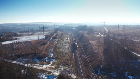 View from above on a freight train. Small cargo train moving on railroad in a sunny winter day. Aerial view.