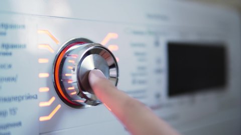Hand turning on and off the switch of the washing machine