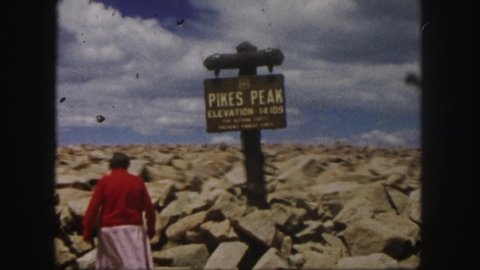 COLORADO SPRINGS USA-1958: Woman Wearing Red Sweater Walks Toward Pikes Peak Sign On A Sunny Day