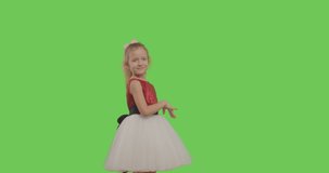 Happy young girl dancing and smiling over green screen background. Young cheerful caucasian child showing thumbs up on Chroma Key. 4k raw video footage slow motion 60 fps