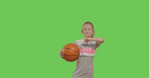 Little child girl portrait stay posing holding basketball ball over green screen background . Girl having fun on chroma Key. 4k video footage slow motion 60 fps