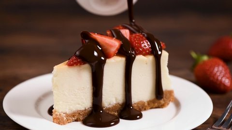 Cheesecake with chocolate sauce. Chocolate sauce pouring over slice of classical New York Cheesecake decorated with strawberries