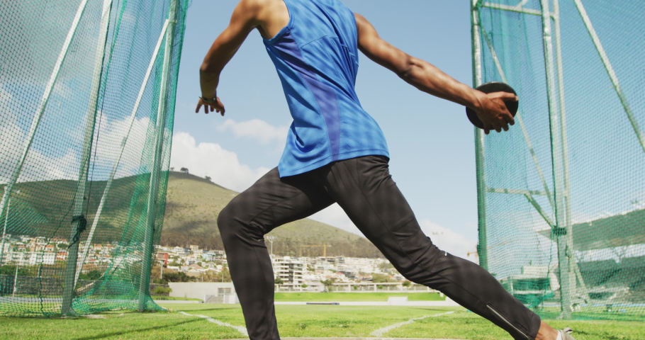 Low angle front view of a mixed race male athlete practicing at a sports stadium, throwing discus, slow motion. Track and Field Sports Training in Stadium. | Shutterstock HD Video #1046238085