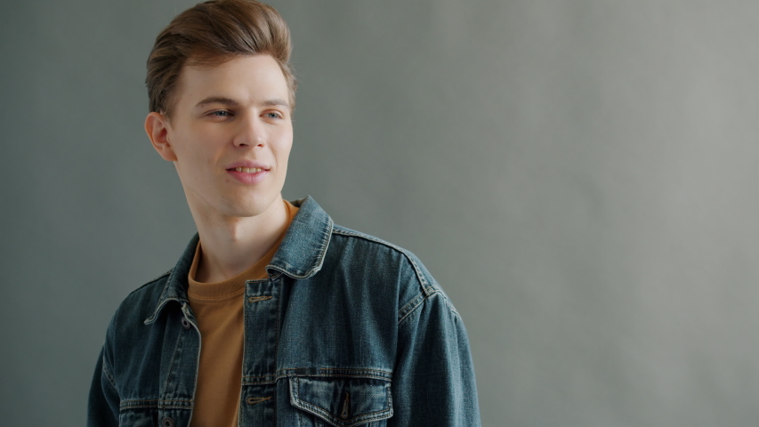 Portrait of smiling guy in trendy clothing posing on gray background looking at camera with happy face alone. Advertising and modern youth concept.