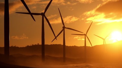 Wind turbine power generators silhouettes at stormy ocean coastline at sunset. Alternative renewable energy production in Philippines 