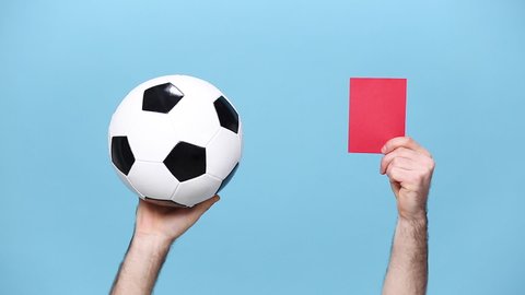 Close up cropped man football fan cheer up support favorite team with soccer ball, hands arms showing red referee judge card isolated on pastel blue background studio. People sport lifestyle concept.