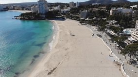 Aerial view of beautiful white sand beach without people, turquoise sea water and resort coastline. South coast of Mallorca island, Baleares, Spain. 4K cinematic footage, bird eye angle. Spring season