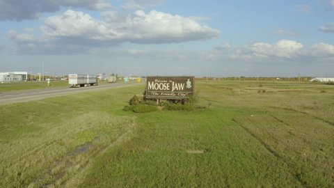View of field and street sign in Moose Jaw, Saskatchewan, Canada. 4k drone footage, pano from right to left above road and prairies. House in the background.