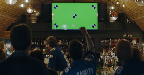 WIDE FIXED Model released, fans watching a game on a large TV in a sport pub, green screen chroma key with tracking points. Shot on ARRI Alexa Mini with Atlas Orion 2x Anamorphic lens