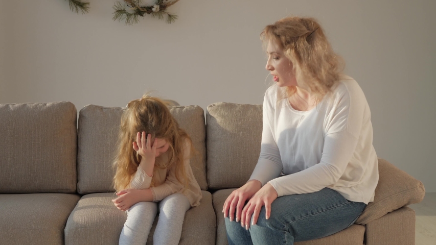 Angry young mother scolding shouting at stubborn fussy little kid daughter demand discipline lecturing disobedient difficult rebellious child ignoring not listening to annoyed mom sit on sofa at home Royalty-Free Stock Footage #1046264005