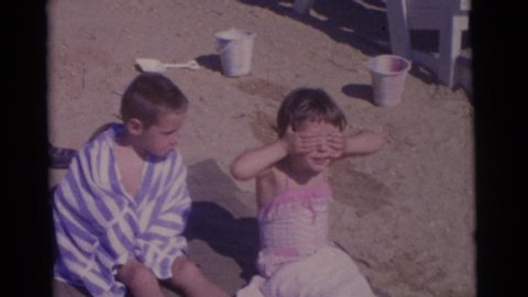 CAMDEN NEW JERSEY USA-1961: Two Children Smile For Camera At Beach A Boy Wrapped In Towel And A Girl In Pink Swimsuit